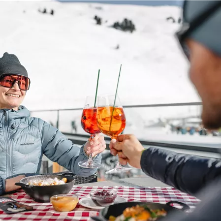 Ein Paar stoßt mit einem Glas Aperol auf den Skitag an.