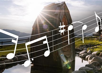 Eine malerische Landschaft mit einer Holzkonstruktion und sanften Hügeln. Musikalische Noten sind im Vordergrund zu sehen.